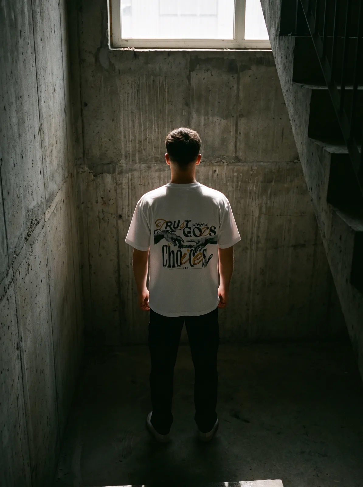 Model wearing the Creation tee in a concrete stairwell